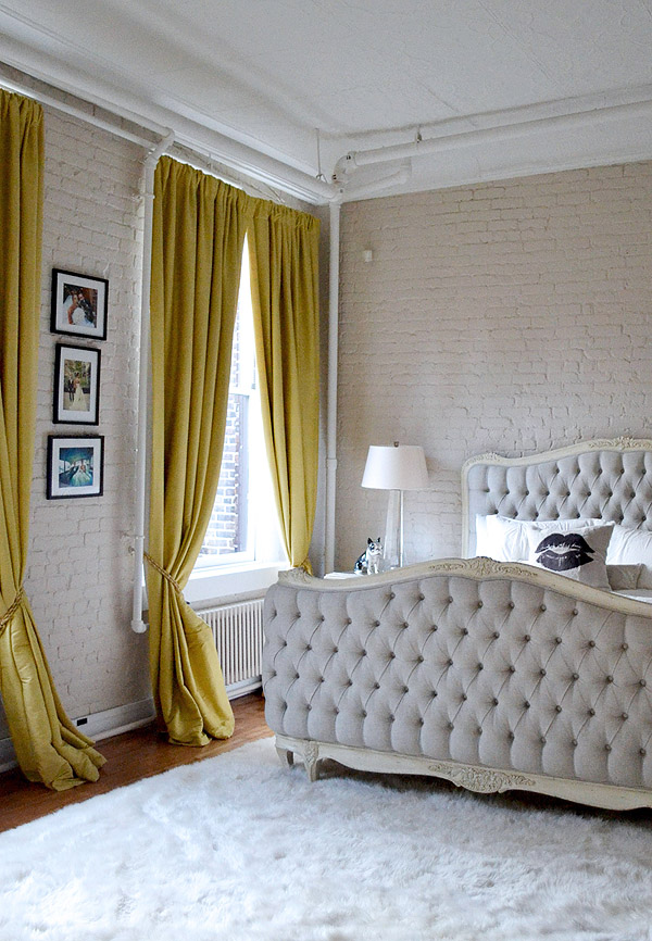 Soho NYC loft Tamra Sanford bedroom brick walls mustard drapes tufted bed