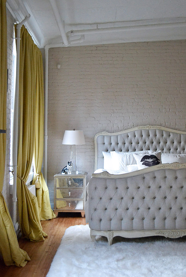 Soho NYC loft Tamra Sanford bedroom brick walls tufted bed mirrored nightstand
